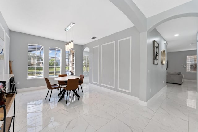 dining room with arched walkways, baseboards, and marble finish floor