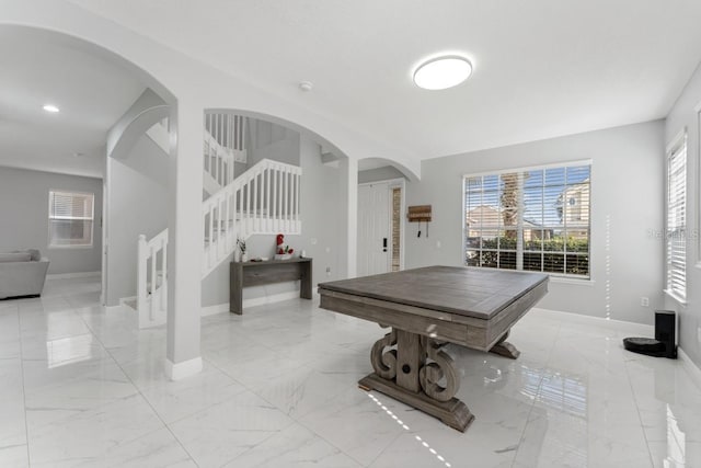 rec room with baseboards, plenty of natural light, and marble finish floor