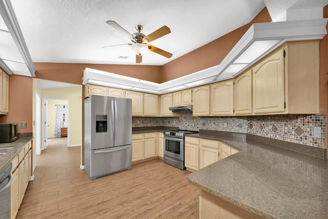 kitchen with a ceiling fan, dark countertops, appliances with stainless steel finishes, light brown cabinets, and light wood-style flooring
