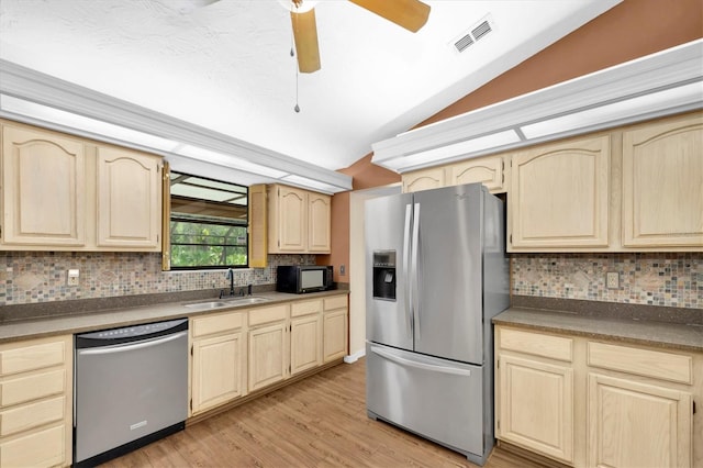 kitchen with visible vents, light brown cabinetry, vaulted ceiling, a sink, and stainless steel appliances