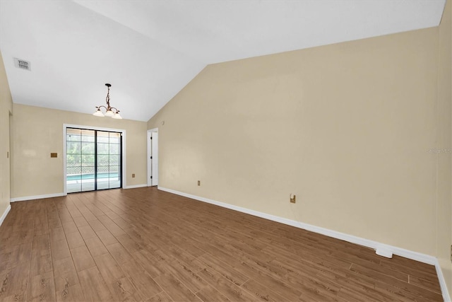 spare room with an inviting chandelier, baseboards, wood finished floors, vaulted ceiling, and visible vents