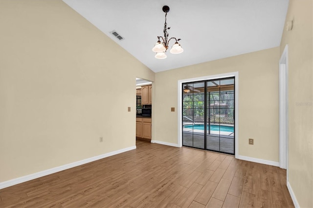 interior space with a chandelier, visible vents, wood finished floors, baseboards, and lofted ceiling