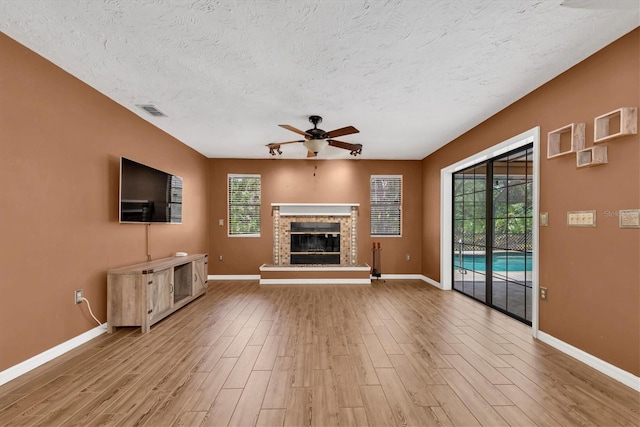 unfurnished living room featuring baseboards, a ceiling fan, a textured ceiling, and wood finished floors