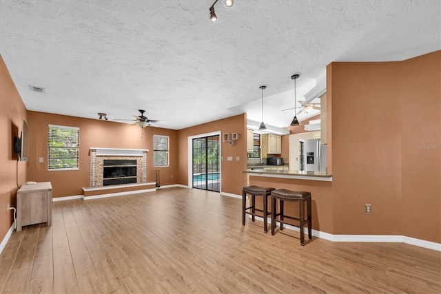 unfurnished living room featuring a ceiling fan, visible vents, and light wood-style flooring