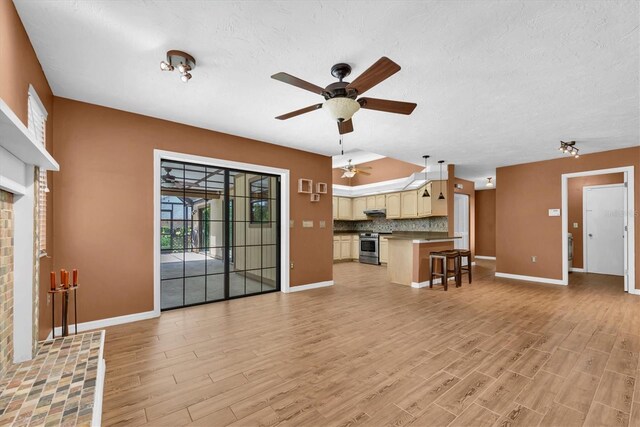 unfurnished living room with baseboards, a ceiling fan, and light wood-style flooring