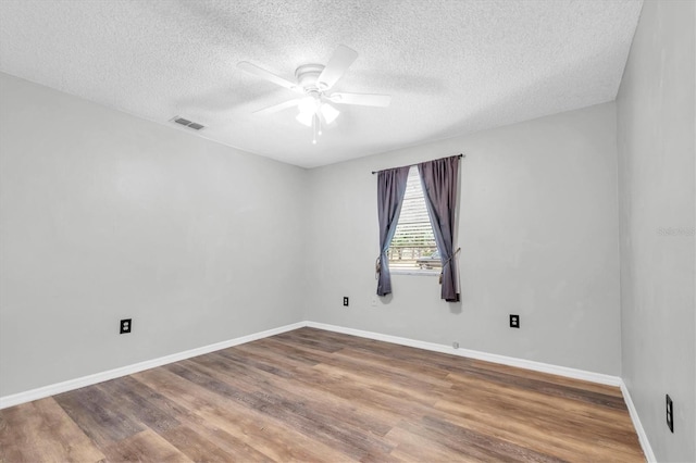 empty room featuring wood finished floors, a ceiling fan, a textured ceiling, and visible vents