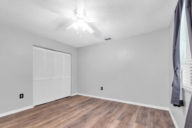 unfurnished bedroom with visible vents, a textured ceiling, wood finished floors, and a closet