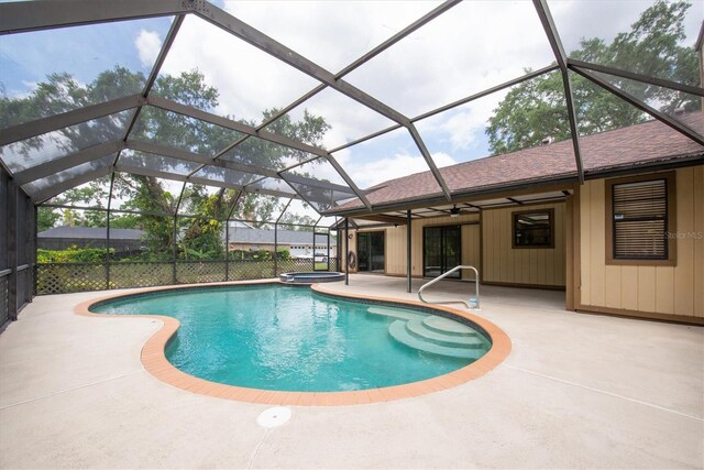 outdoor pool with a ceiling fan, glass enclosure, an in ground hot tub, and a patio area