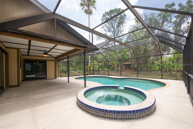 view of swimming pool with glass enclosure, a pool with connected hot tub, a ceiling fan, and a patio area