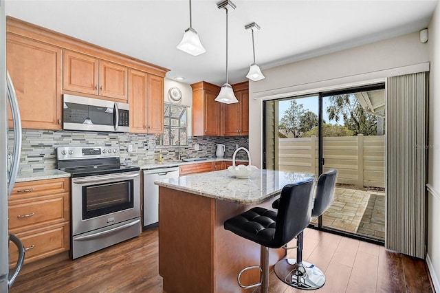 7817 Pine Trace Dr Unit 15, Sarasota, FL 34243 - kitchen with decorative backsplash, dark wood-style flooring, appliances with stainless steel finishes, hanging light fixtures, and light stone counters