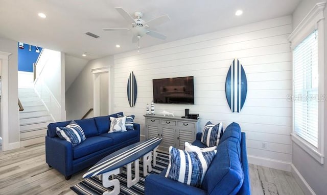 living area with baseboards, light wood-style floors, ceiling fan, recessed lighting, and wood walls