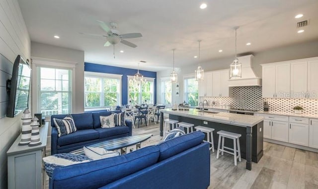 living area featuring a ceiling fan, light wood-style flooring, recessed lighting, and a chandelier
