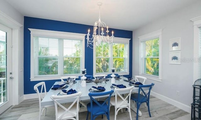 dining area with a chandelier, baseboards, and light wood-style floors
