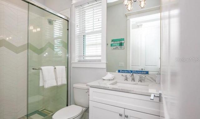 bathroom with a shower stall, toilet, vanity, and a chandelier