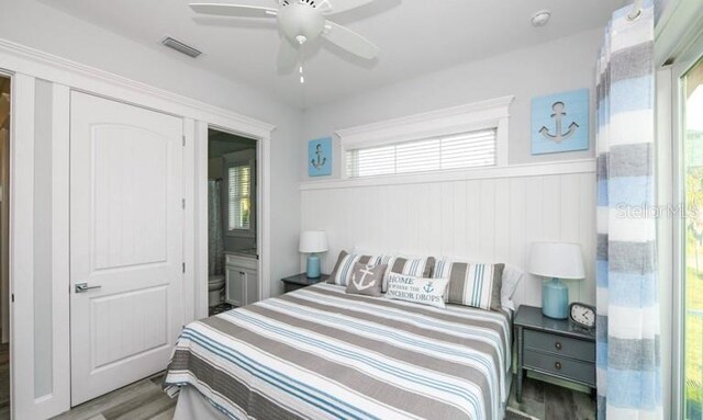 bedroom featuring wood finished floors, a ceiling fan, and wainscoting