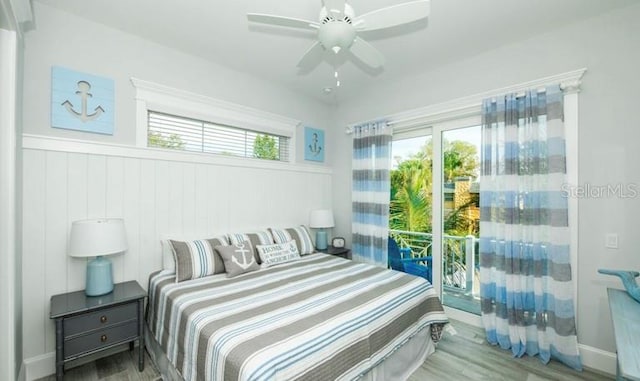 bedroom featuring wood finished floors, a wainscoted wall, and a ceiling fan