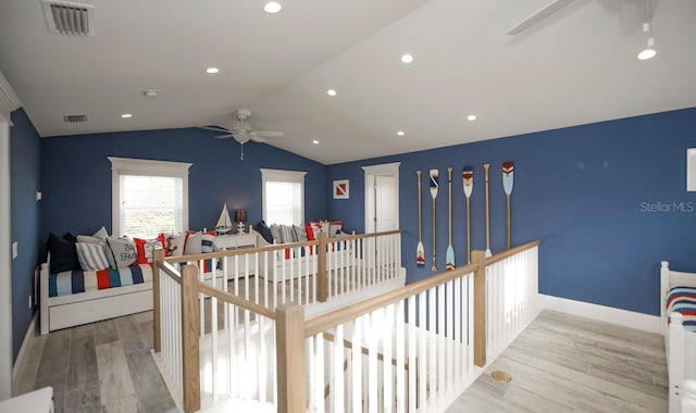 hall with wood finished floors, an upstairs landing, lofted ceiling, baseboards, and recessed lighting