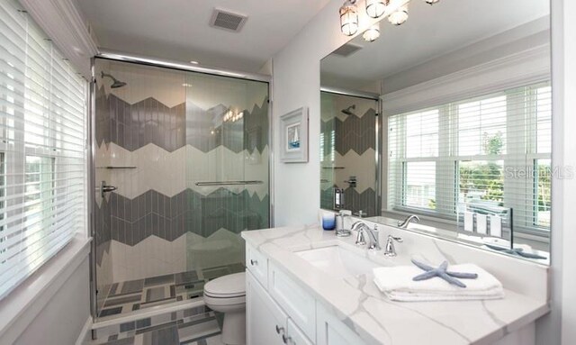 bathroom with toilet, a shower stall, a chandelier, and vanity