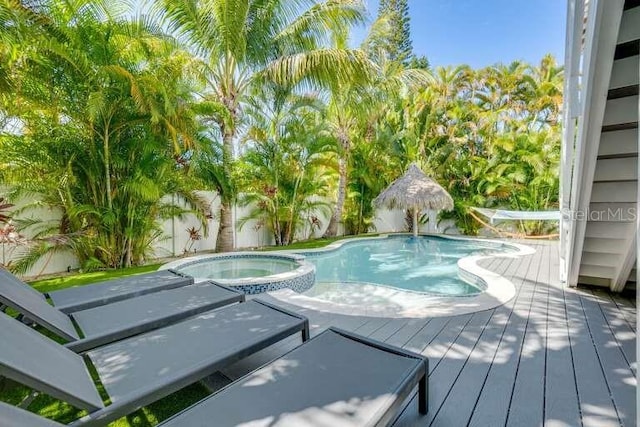 view of swimming pool with a deck, a fenced backyard, and a pool with connected hot tub