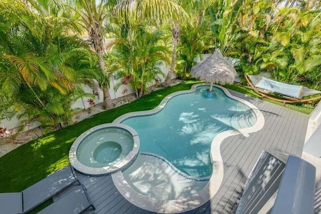 outdoor pool with an in-ground hot tub, a wooden deck, and a fenced backyard