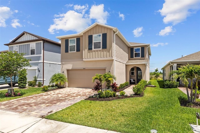 11430 Gallatin Trl, Parrish, FL 34219 - view of front of property with board and batten siding, an attached garage, decorative driveway, a front lawn, and stucco siding