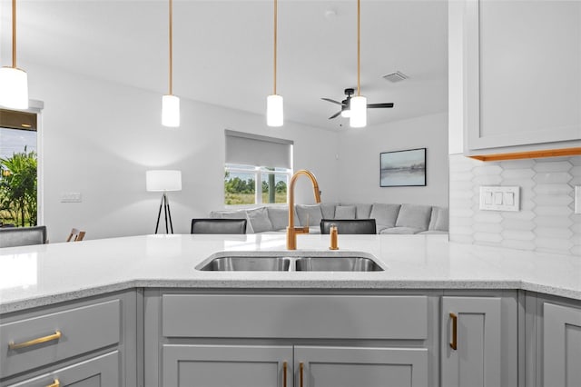 11430 Gallatin Trl, Parrish, FL 34219 - kitchen featuring a sink, backsplash, open floor plan, light stone counters, and decorative light fixtures