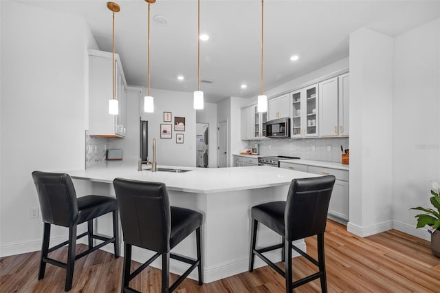 11430 Gallatin Trl, Parrish, FL 34219 - kitchen featuring appliances with stainless steel finishes, a sink, a peninsula, a kitchen breakfast bar, and light wood finished floors