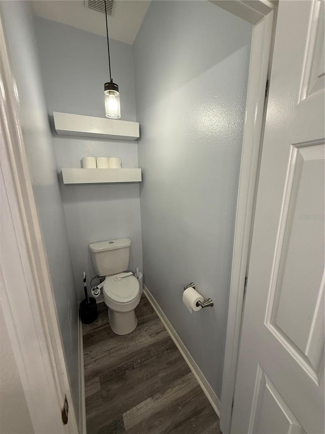 bathroom featuring baseboards, wood finished floors, visible vents, and toilet