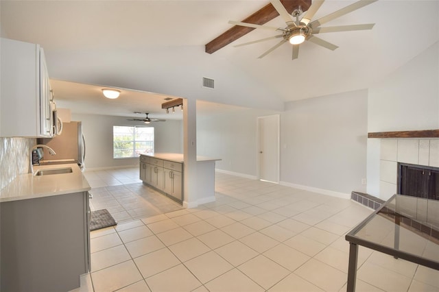 2402 16th St W, Palmetto, FL 34221 - kitchen with a ceiling fan, a sink, light countertops, a tiled fireplace, and light tile patterned floors