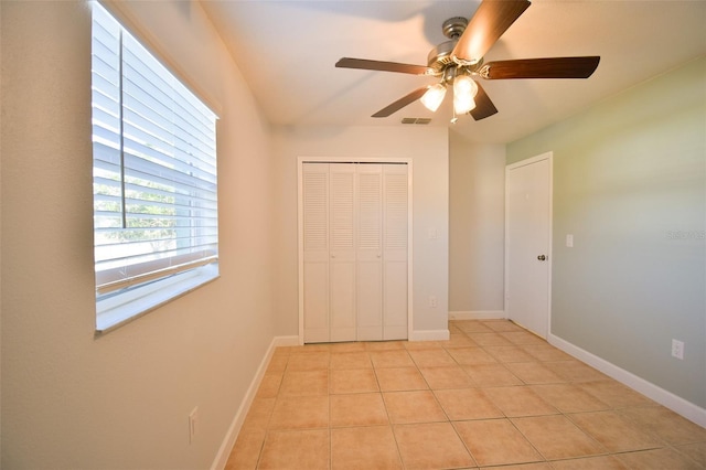 2402 16th St W, Palmetto, FL 34221 - unfurnished bedroom with light tile patterned flooring, a closet, baseboards, and ceiling fan