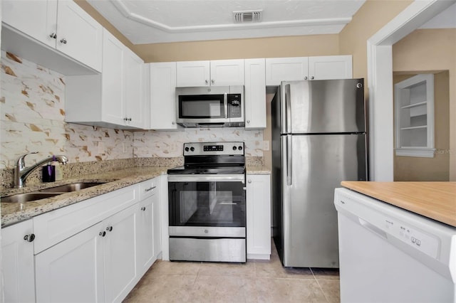 1830 Virginia Dr, Bradenton, FL 34205 - kitchen featuring visible vents, a sink, white cabinetry, tasteful backsplash, and appliances with stainless steel finishes