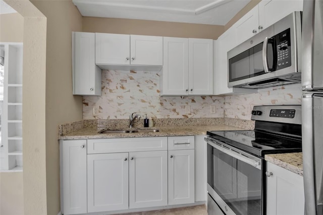 1830 Virginia Dr, Bradenton, FL 34205 - kitchen featuring light stone countertops, a sink, white cabinets, stainless steel appliances, and tasteful backsplash