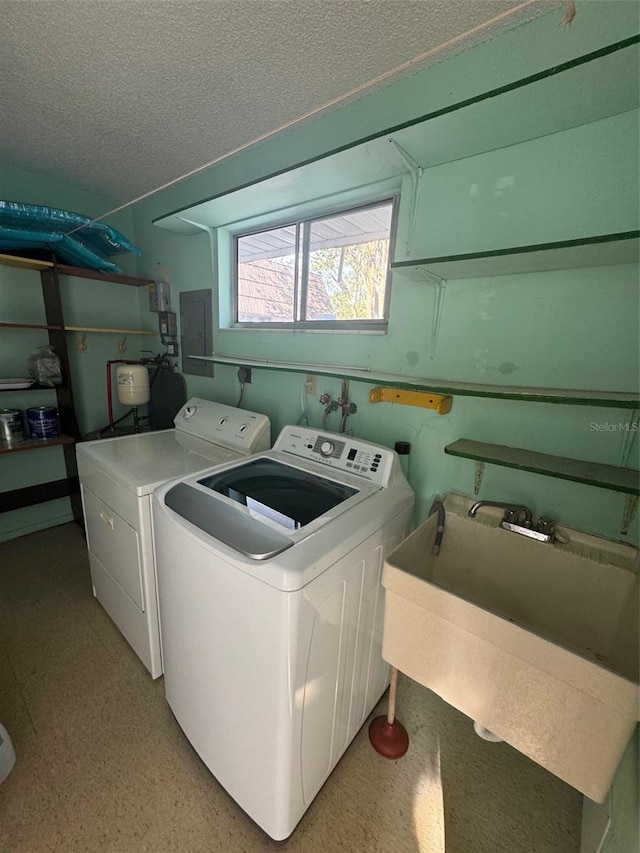 laundry area featuring a textured ceiling, laundry area, washing machine and dryer, and electric panel
