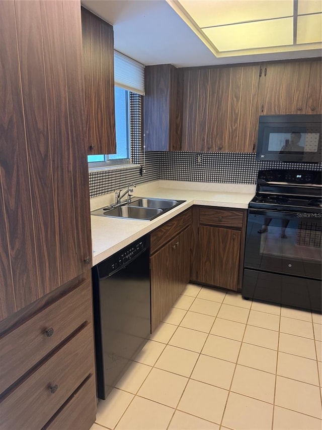 kitchen with a sink, light countertops, light tile patterned floors, backsplash, and black appliances