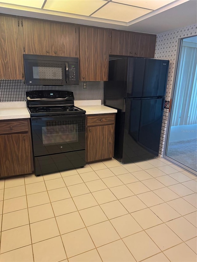 kitchen featuring light countertops, light tile patterned flooring, backsplash, and black appliances