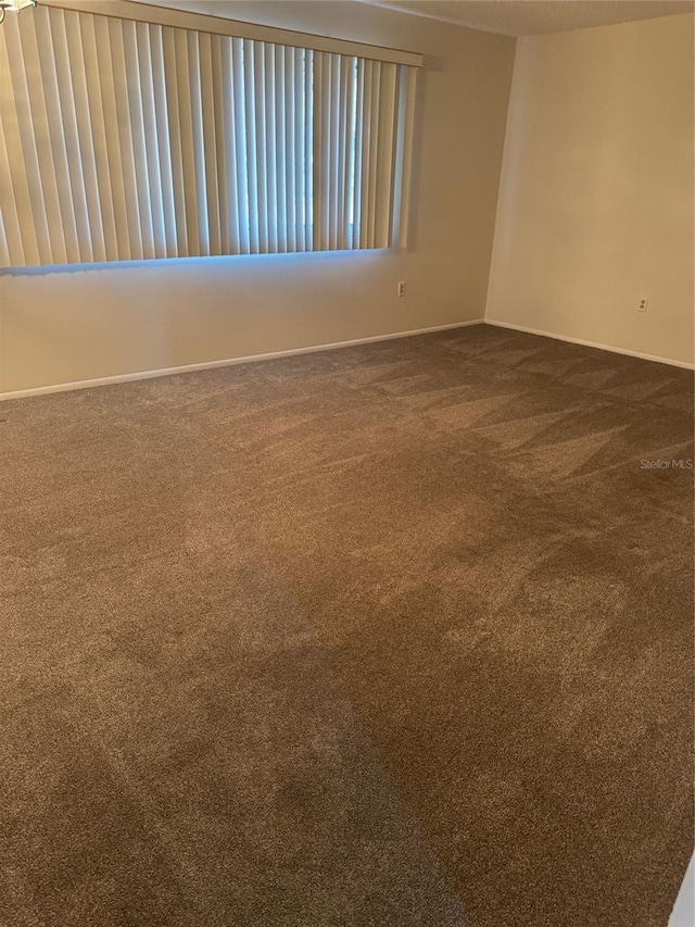 carpeted empty room featuring baseboards