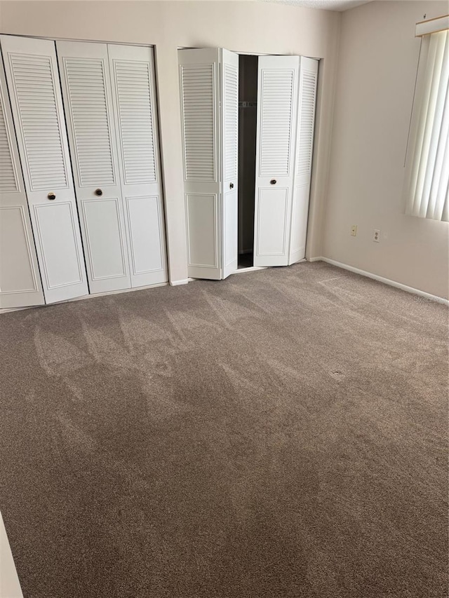 unfurnished bedroom with multiple closets, baseboards, and carpet flooring