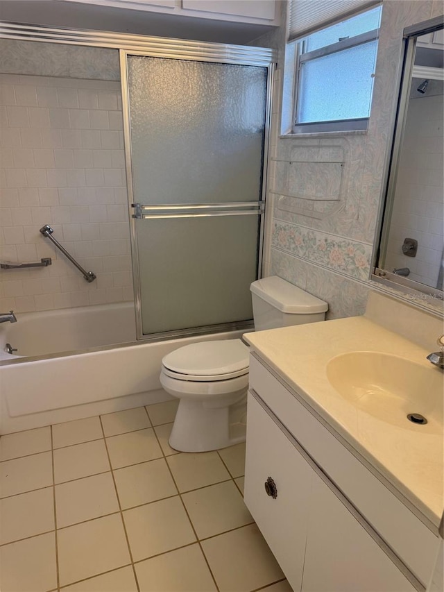 full bath featuring vanity, tile patterned flooring, bath / shower combo with glass door, and toilet