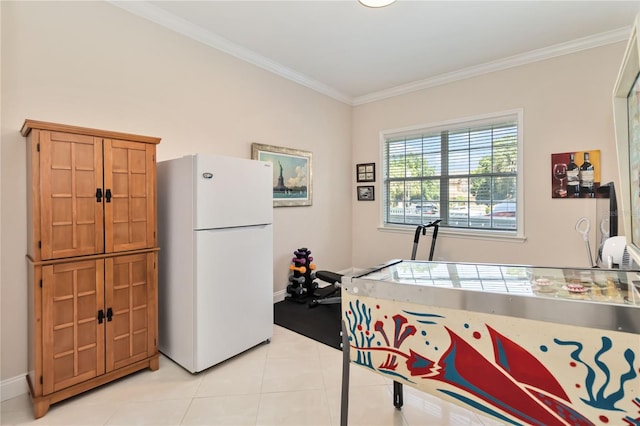 kitchen with freestanding refrigerator, light tile patterned floors, ornamental molding, brown cabinetry, and baseboards