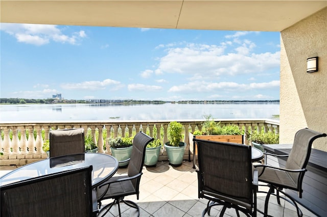 balcony with outdoor dining area, a water view, and a patio area