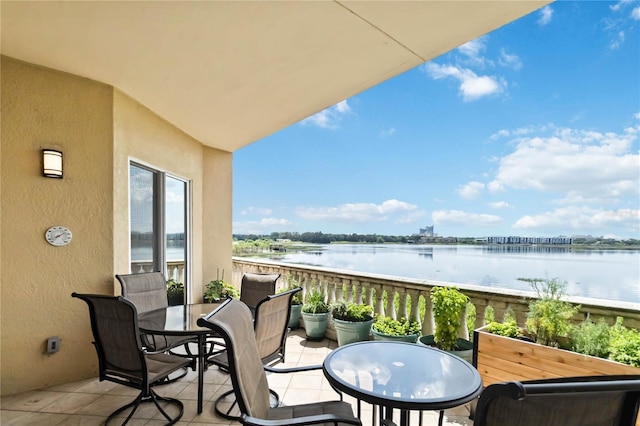 balcony featuring a water view and outdoor dining area