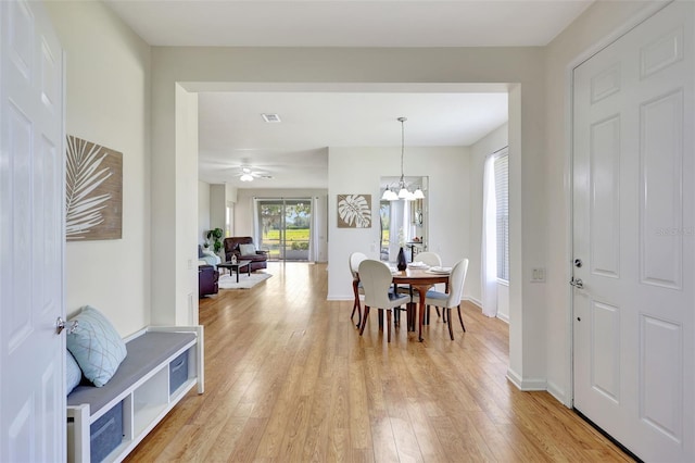 dining space featuring light wood-style floors, baseboards, a notable chandelier, and visible vents
