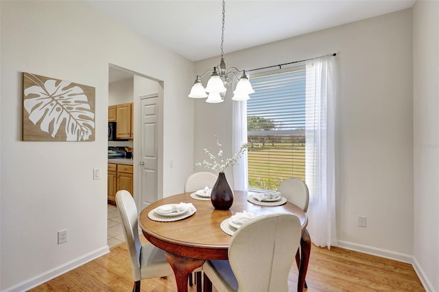 dining space with baseboards, light wood finished floors, and a notable chandelier