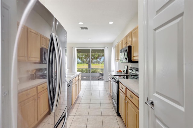 kitchen featuring light tile patterned flooring, light brown cabinets, light countertops, stainless steel appliances, and visible vents