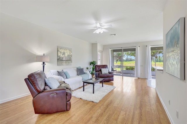 living room featuring baseboards, a ceiling fan, light wood-style flooring, and visible vents
