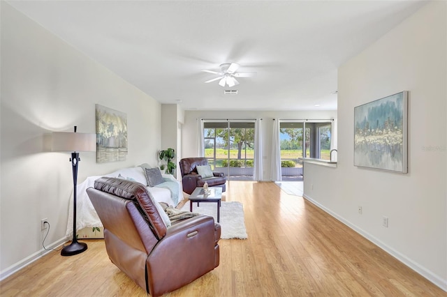 living room featuring baseboards, a ceiling fan, wood finished floors, and visible vents