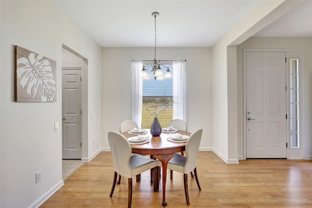 dining room with baseboards, light wood finished floors, and a chandelier