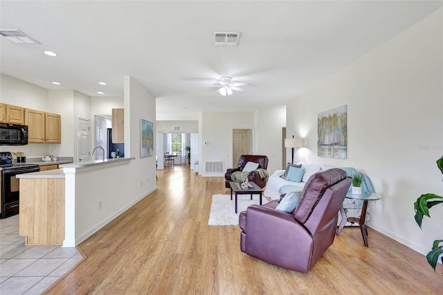 living area featuring visible vents, a ceiling fan, and light wood-type flooring