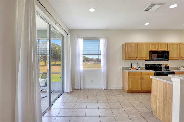 kitchen featuring visible vents, light brown cabinetry, baseboards, light countertops, and black appliances