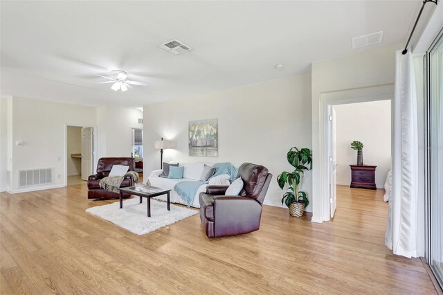 living room with visible vents, light wood-style floors, and ceiling fan